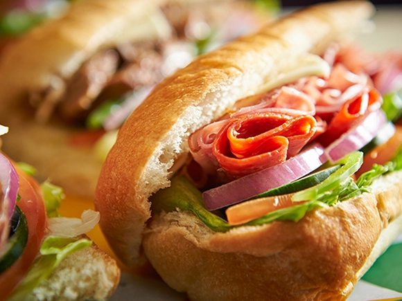 front facing view of a sub sandwich with ham, salami, onions, tomatoes, bell peppers, cucumbers, lettuce and cheese